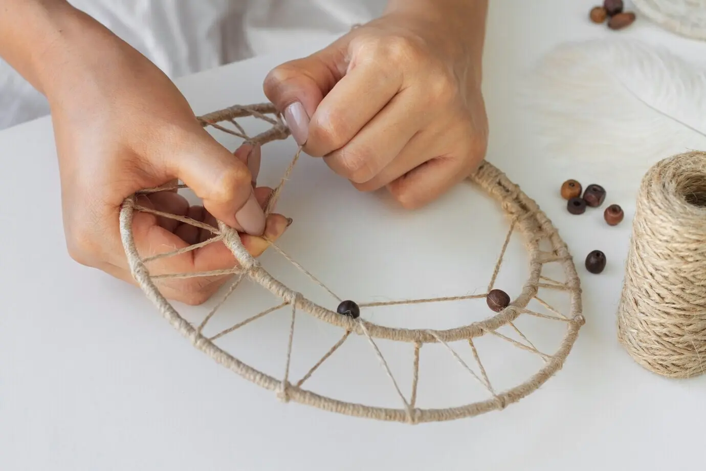 Nahaufnahme einer Person, die an einem Traumfänger arbeitet.